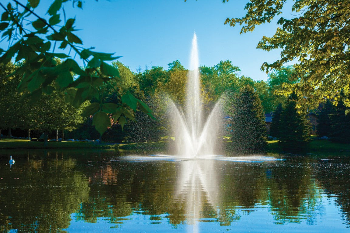 A fountain with a solid brass center nozzle surrounded by eight individual brass nozzles, situated in a pond.