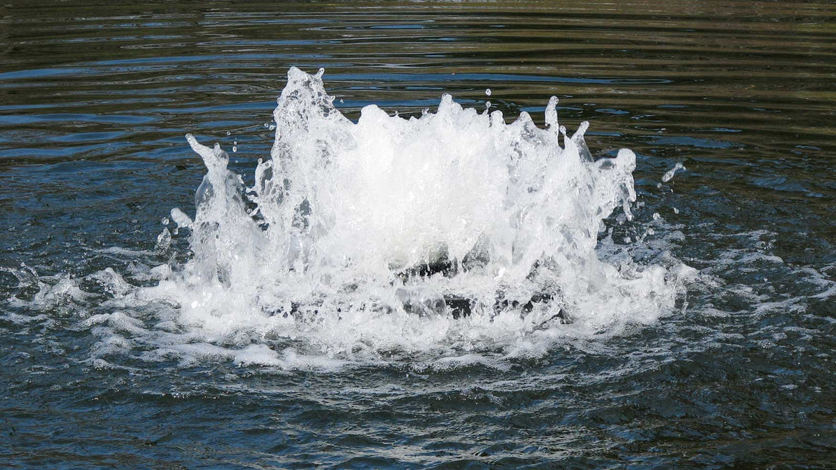 Water fountain or water feature with splashing water in a pond